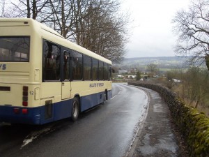 A cream and blue bus driving down a road.