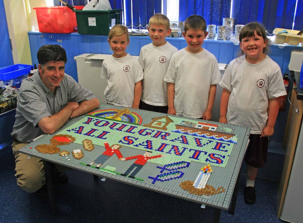Four primary school children and a teacher displaying a mosaic.