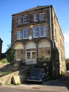 A 3 story stone building with large shop windows on the bottom floor.