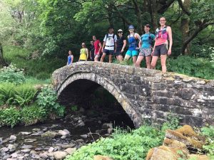 Runners stood on a stone bridge over a river.